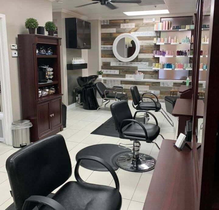 Inside Suite 2 Salon: black styling chairs, a shampoo station and a reclaimed-wood wall lined with hair care products around a round mirror