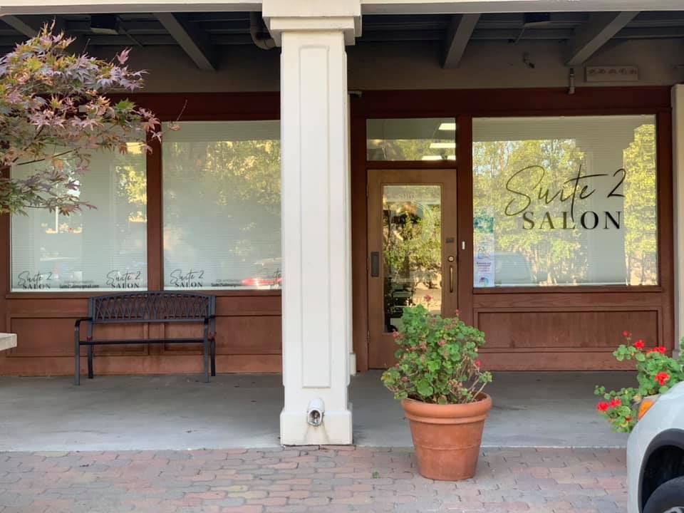 The Suite 2 Salon storefront on Gregory Lane by day, with a bench and potted flowers under the arcade
