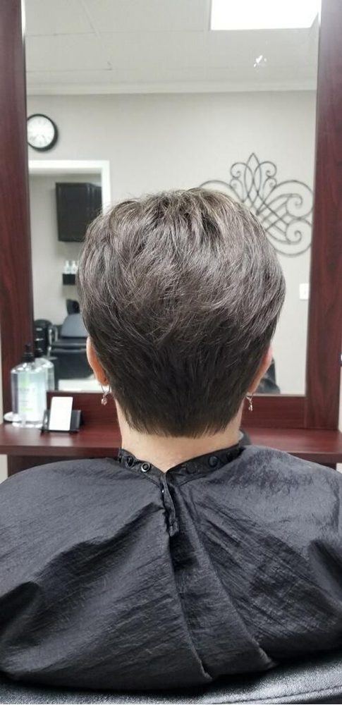 Back view of a short, layered ash-brown cut in front of the salon mirror